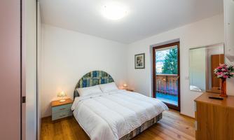 A cozy bedroom with a double bed and elegant bedding. The room has wooden flooring and a window with a view outside.