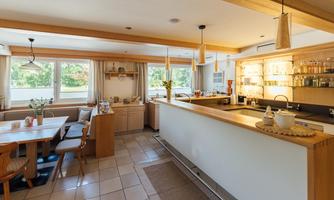 A bright kitchen with wood details and modern appliances. The dining area is cozy and inviting, with a table and chairs.