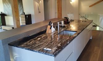 A modern kitchen with an elegant stone surface and wooden details. The open layout creates a bright and inviting atmosphere.