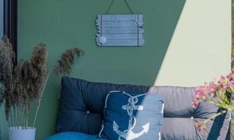 A cozy seating area with blue cushions and a green wall. In the background, decorative elements and plants can be seen.