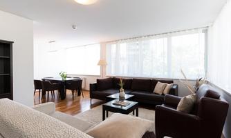 A modern living room with a bright color scheme and large windows. The furniture is stylishly and comfortably arranged.