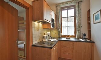 A modern kitchen with wooden cabinets and a window that lets in plenty of light. Cooking utensils and a coffee machine are on the countertop.