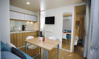 A modern room with a small kitchen, a dining table, and a cozy living area. The decor is bright and inviting with wooden flooring and stylish furniture.
