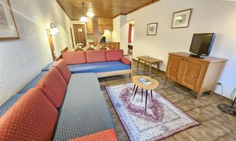 A cozy living space with red and blue sofas. A coffee table and a television complement the pleasant atmosphere.
