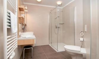 A modern bathroom with a shower, sink, and toilet. The walls are in neutral tones, and the ambiance is bright and inviting.