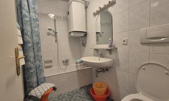 A small bathroom with a shower and a bathtub. There is a sink, a toilet, and a window decoration.