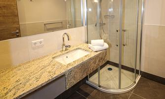A modern bathroom with a glass shower and an elegant marble surface. The walls are bright and the atmosphere feels inviting and clean.