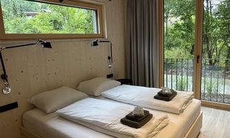 A cozy bedroom with two beds and large windows. The view of the greenery creates a relaxing atmosphere.