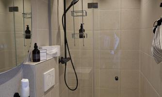 A modern bathroom with a glass shower and elegant fixtures. The room is bright and designed in a minimalist style.