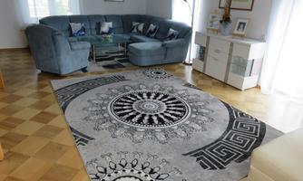 A modern living room with a large, comfortable sofa and a stylish rug. The room is bright and friendly, with elegant furnishings.