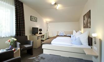 A bright and modern bedroom with two beds and elegant decoration. There is a television, a small table, and comfortable chairs.