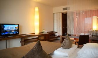 A modern hotel room with comfortable beds and a stylish interior design. A television and a cozy seating area are also available.