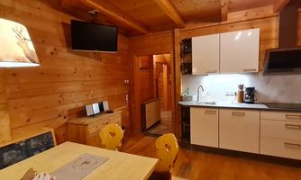 A cozy kitchen in a wooden house with modern design. The space is bright and inviting, with a dining area and modern amenities.