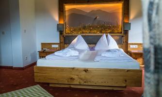 A cozy bedroom with a large double bed and two pillows. The wooden paneling and soft lighting create a warm atmosphere.