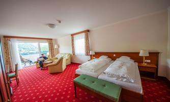 A comfortable hotel room with two single beds and a cozy seating area. Large windows offer a view of the landscape.