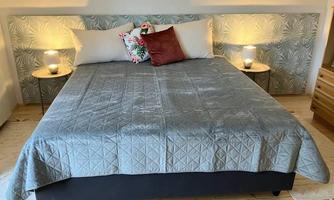 A cozy bedroom with a large bed and bright, modern bedding. Two bedside tables with lamps flanking the bed for a calm atmosphere.