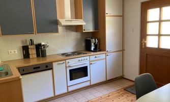 A bright kitchen with wooden shelves and modern appliances. The combination of wood and white cabinets gives it an inviting character.