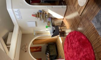 A bright living space with a red carpet and a desk. In the background, you can see a cozy seating area and open doors.