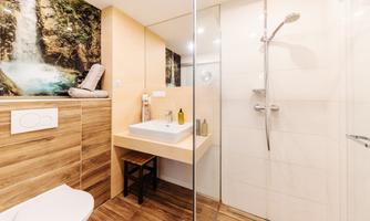 A modern bathroom with a shower and a sink. A natural wall design with a waterfall conveys a relaxing atmosphere.