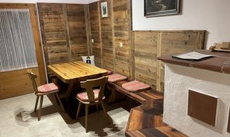 A cozy dining area with a wooden communal table and comfortable seating. The walls are made of wood, creating a warm atmosphere.