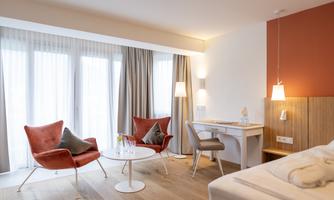 A modern room with comfortable red armchairs and a round table. Large windows provide plenty of light and a bright atmosphere.