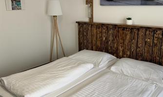 A bright bedroom with two single beds and rustic wood decor. A picture of a motorcycle hangs on the wall.