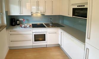 Modern kitchen with white cabinets and a clear countertop. An elegant stove and a built-in oven are available.