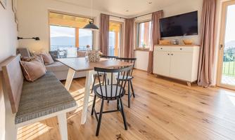 A modern living and dining room with wooden flooring. Large windows let in plenty of light and provide a beautiful view.