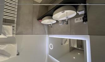 A modern bathroom with two sinks and a lit mirror.