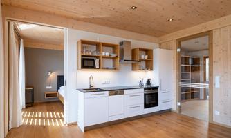 Modern kitchen with wooden shelves and a large window. The room is bright and cozily designed.