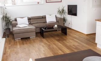 A modern living room with a beige couch and a black coffee table. Bright walls and a natural wooden floor create a friendly atmosphere.