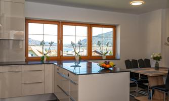 A modern kitchen with white cabinets and a large kitchen island. The windows offer a beautiful view of the landscape.