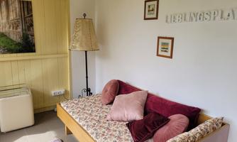 A cozy room with a sofa and decorative cushions. On the wall is the word "Favorite Place" and there is a floor lamp.