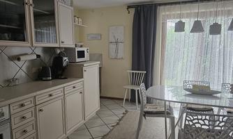 A modern kitchen with a dining area and plenty of natural light. The furniture is bright and inviting, with a cozy atmosphere.
