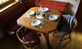 A rustic wooden table with elegant plates and cutlery. Cozy seating areas create an inviting atmosphere.