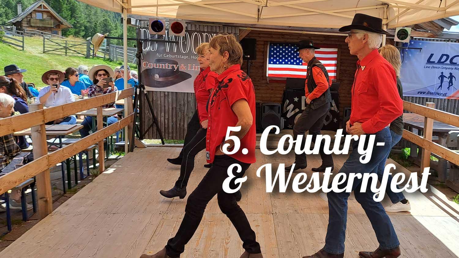 Country-Westernfest-Tänzer in roten Hemden tanzen auf einer Holzplattform vor Publikum.