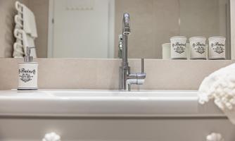A modern bathroom with a sink and a faucet. Stylish toothbrush holders and a soap dispenser are on the sink, and a towel holder is also visible.