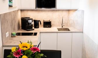 A modern kitchen with white cabinets and high-quality appliances. A vase with colorful flowers is on the table.