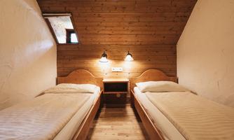 A cozy bedroom with two single beds and wooden paneling. Soft lighting creates a relaxed atmosphere.