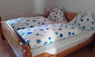 A cozy bedroom with a wooden double bed. The bedding is decorated with blue floral patterns.