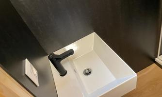 A modern sink with a black faucet. It is placed in a simple and elegant room.