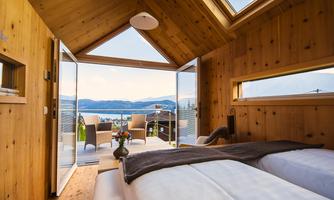 A modern bedroom with wooden paneling and large windows. The view of the landscape outside is breathtaking.
