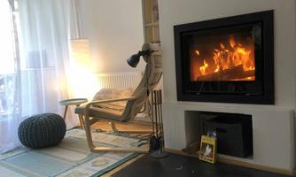 A cozy living space with a fireplace and a wooden chair. The fire in the fireplace creates a warm atmosphere.