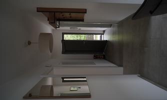 A bright hallway with white walls and large mirrors. The door at the end of the hallway opens to the outside area.