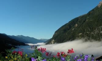 A picturesque landscape with mountains and clouds in the morning. In the foreground, colorful flowers are blooming.