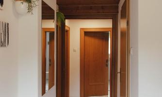 A bright hallway with a wooden ceiling and white walls. Several doors lead to different rooms.