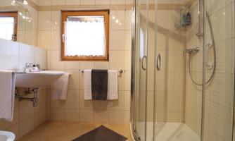 A modern bathroom with a shower and a sink. There are bright tiles and a window that lets in daylight.