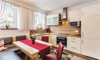 A modern kitchen with a wooden table and red chairs. Large windows let in plenty of light and create a calm atmosphere.