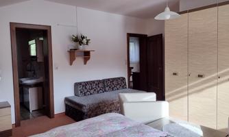 A cozy room with a double bed, a sofa, and a wardrobe. The bathroom is visible in the background.