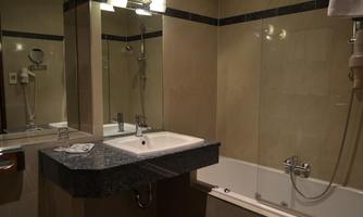 A modern bathroom with a bathtub and a granite sink. The walls are in neutral tones, and there is a mirror above the sink.